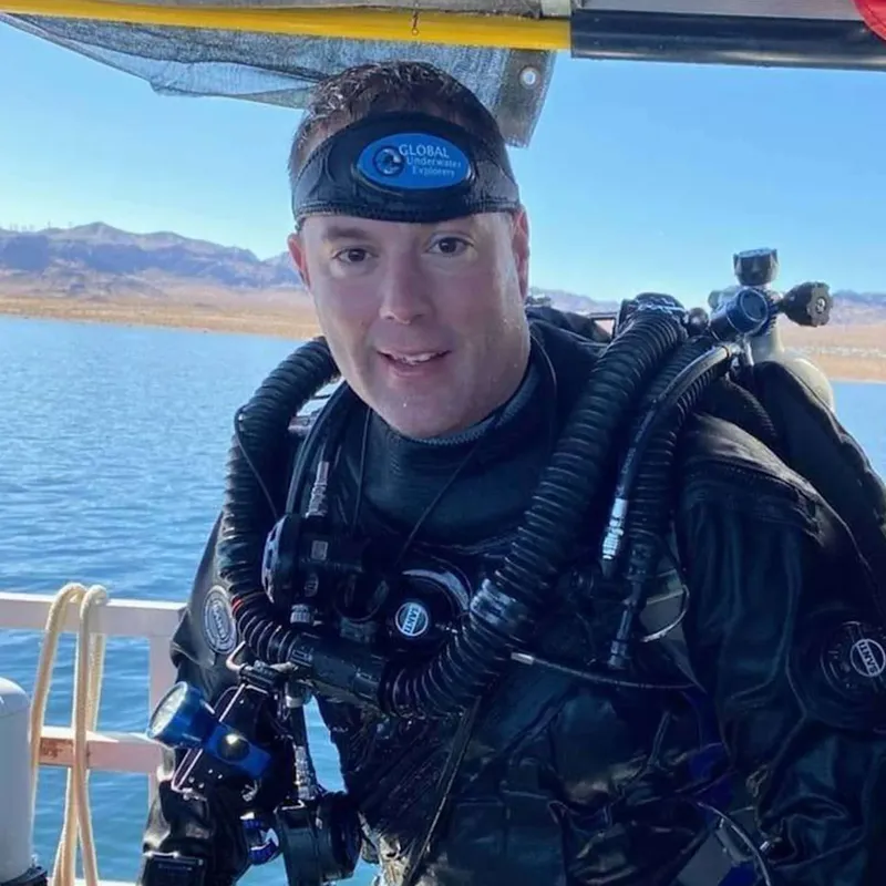 Plongeur souriant en combinaison complète sur un bateau en mer