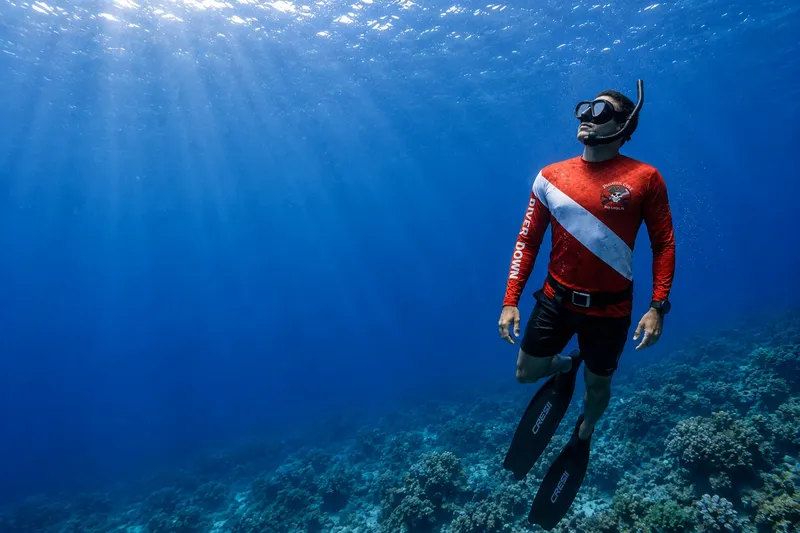 Plongeur en apnée, regardant vers le haut dans l'eau bleue claire