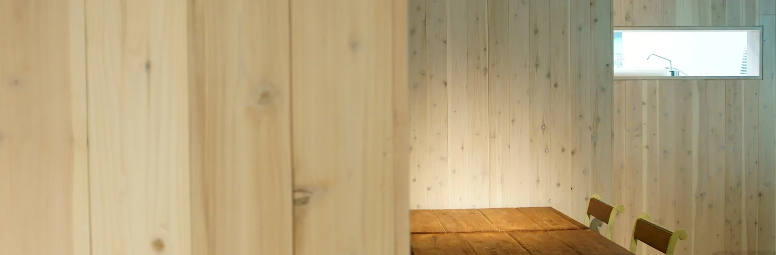 Intérieur clair avec murs en bois, table et chaises simples
