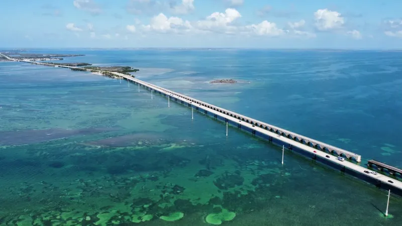 Vue aérienne d'un long pont sur une mer turquoise et peu profonde