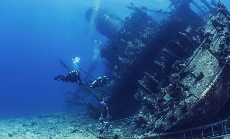 Deux plongeurs explorent l'épave d'un grand navire sous-marin