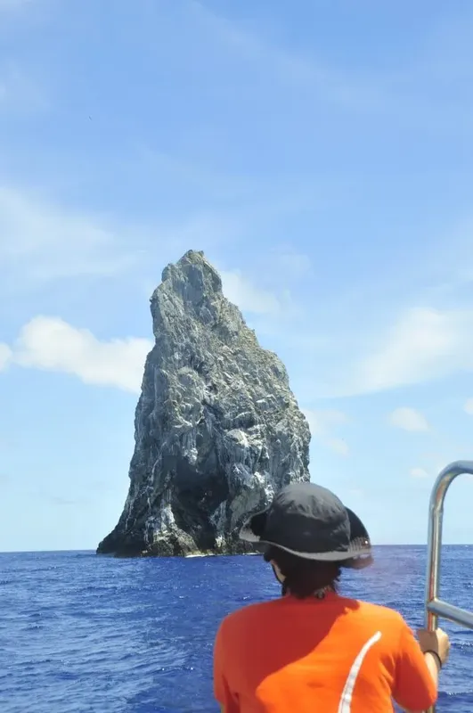 Vue d'une personne observant un rocher escarpé en mer
