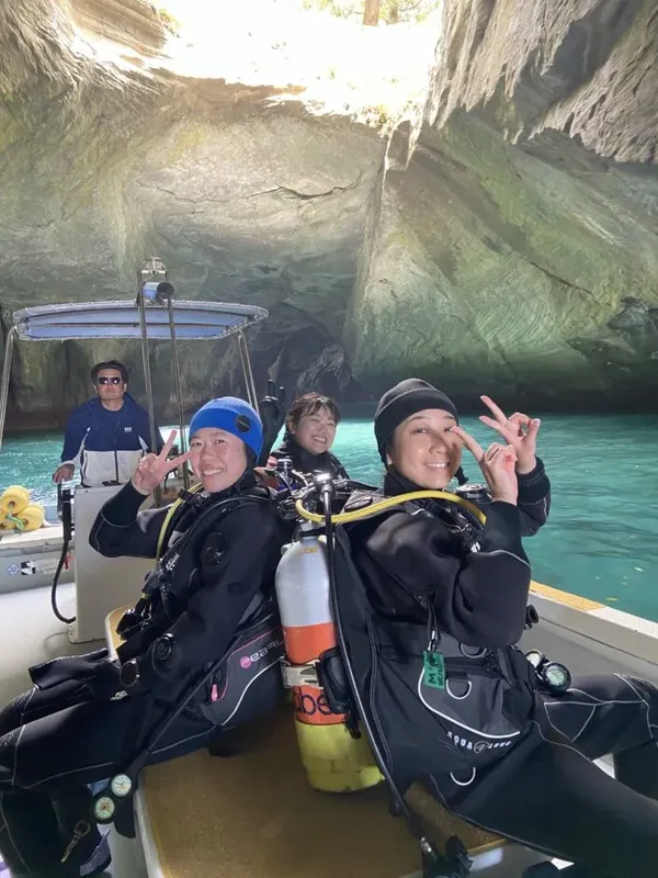 Plongeurs souriants sur un bateau, faisant des signes de victoire