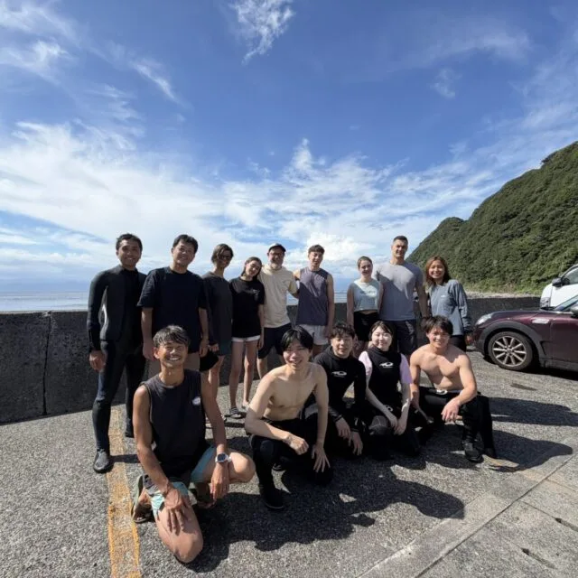 Groupe de personnes souriantes posant sur un parking en bord de mer