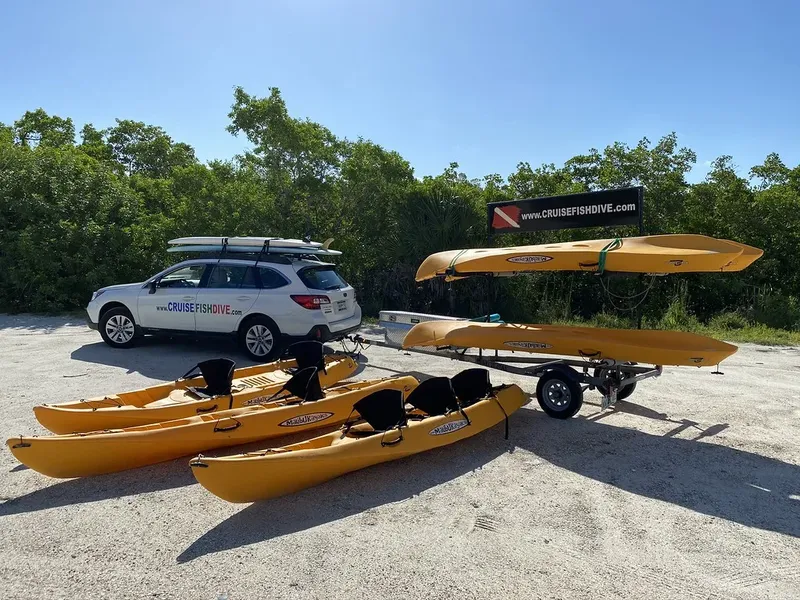 voiture blanche et kayaks jaunes sur un parking en sable