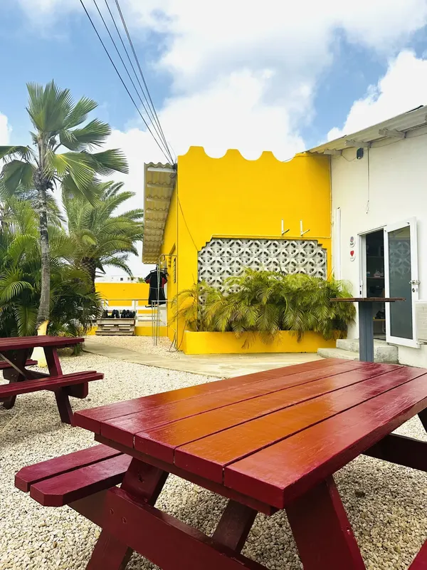 Cour extérieure d'un centre de plongée avec tables et végétation tropicale
