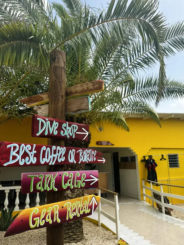 Panneau indicateur coloré devant un bâtiment jaune, matériel de plongée visible