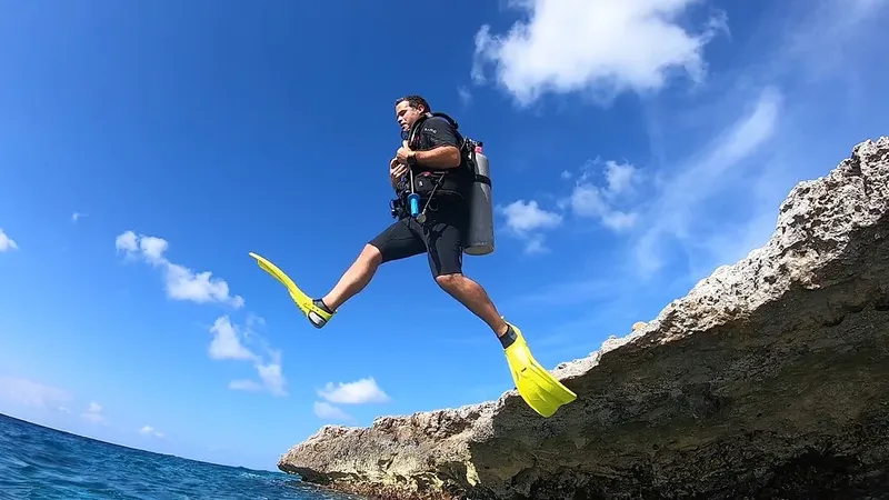 Plongeur s'apprête à sauter d'une falaise rocheuse dans l'eau bleue