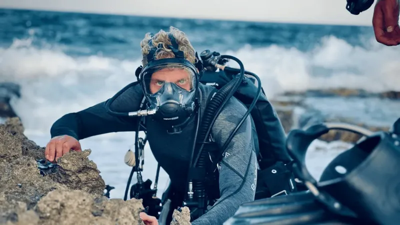 Plongeur avec équipement complet explore un fond rocheux en mer