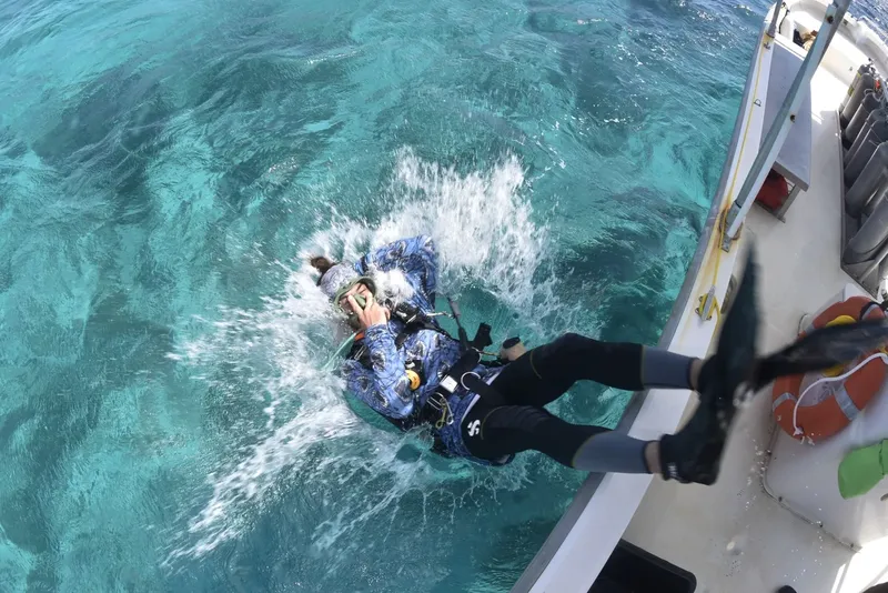 Plongeur entrant dans l'eau depuis un bateau, équipé et prêt