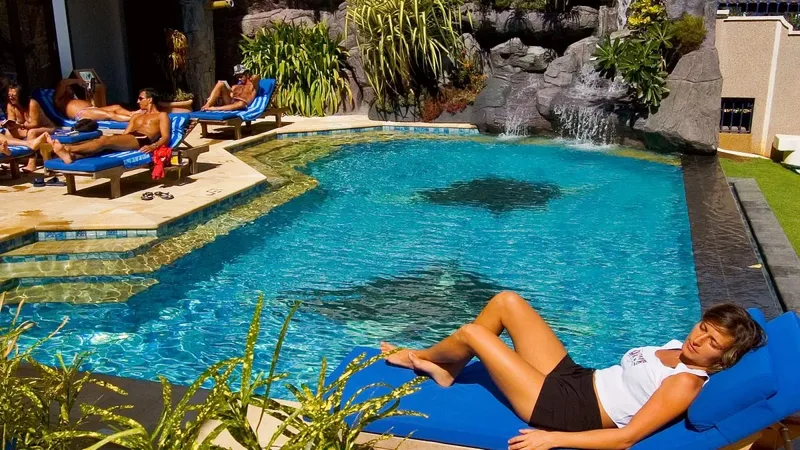 Personnes se relaxent au bord d'une piscine avec une raie manta