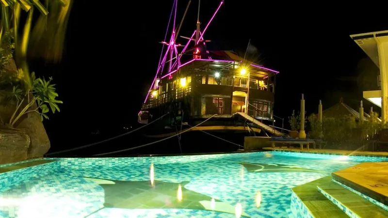 Bâtiment illuminé de couleurs vives au bord d'une piscine la nuit