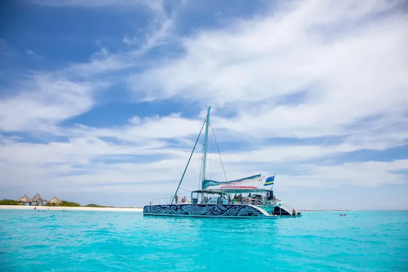 Catamaran turquoise naviguant sur une mer calme avec des passagers