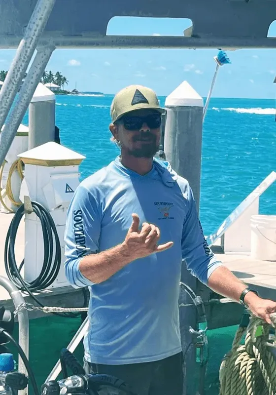 Homme sur un bateau de plongée, faisant le signe de la main