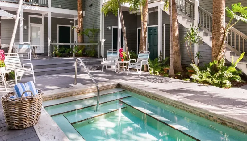 Terrasse avec piscine, mobilier de jardin et végétation tropicale ensoleillée