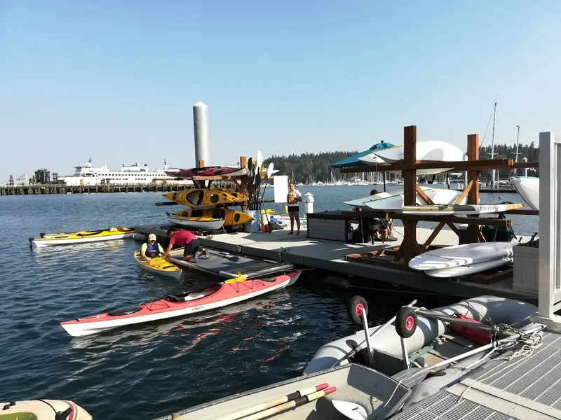Personnes manipulant des kayaks et planches de paddle sur un ponton
