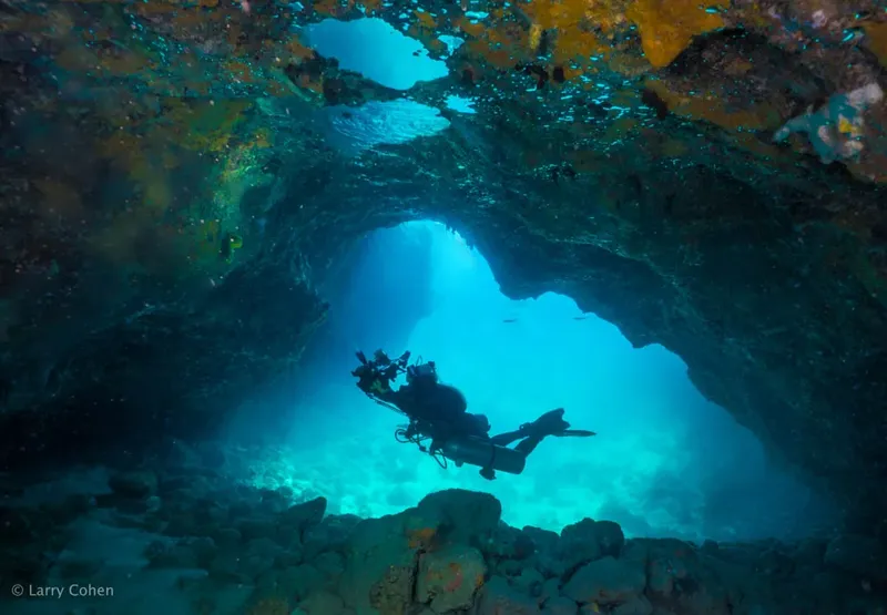 Plongeur explorant une grotte sous-marine avec une lumière bleutée