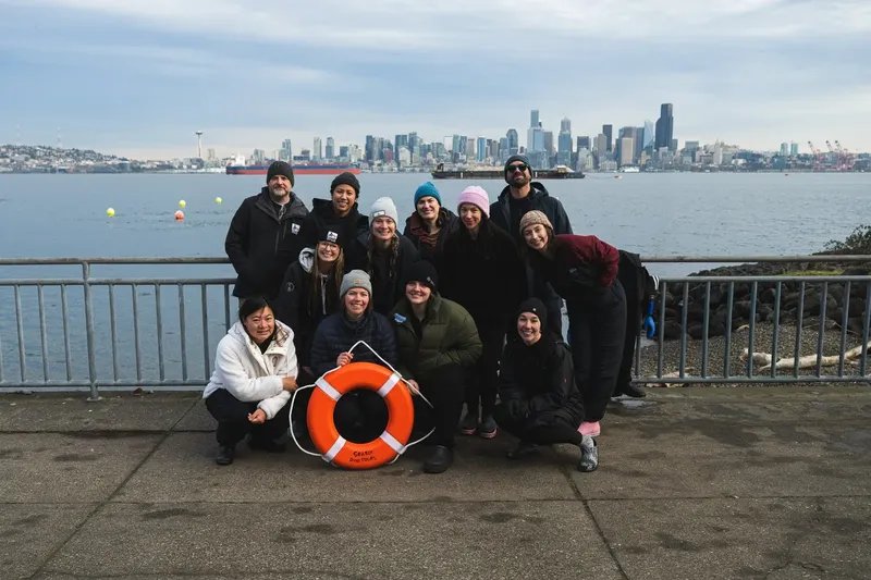 Groupe de personnes souriantes posant sur un quai avec vue sur la mer