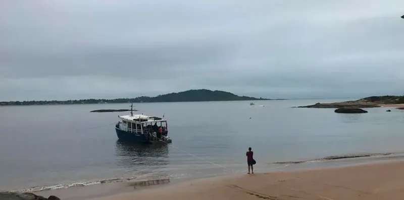 Bateau de plongée amarré près d'une plage avec une personne debout