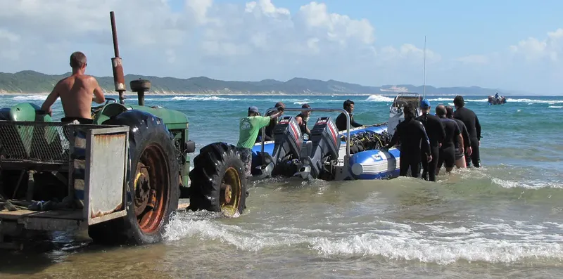 Plongeurs sortant d'un bateau pneumatique tracté par un tracteur sur la plage
