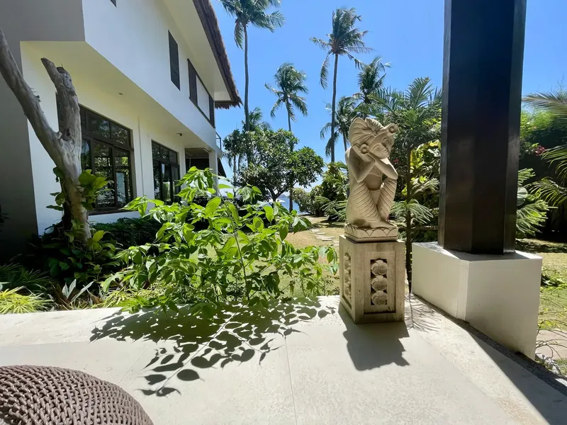 Bâtiment blanc avec statue, végétation tropicale et ciel bleu clair