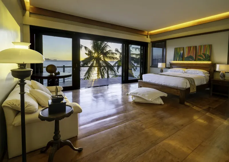 Chambre avec vue sur mer, lit, canapé, décoration tropicale, lumière