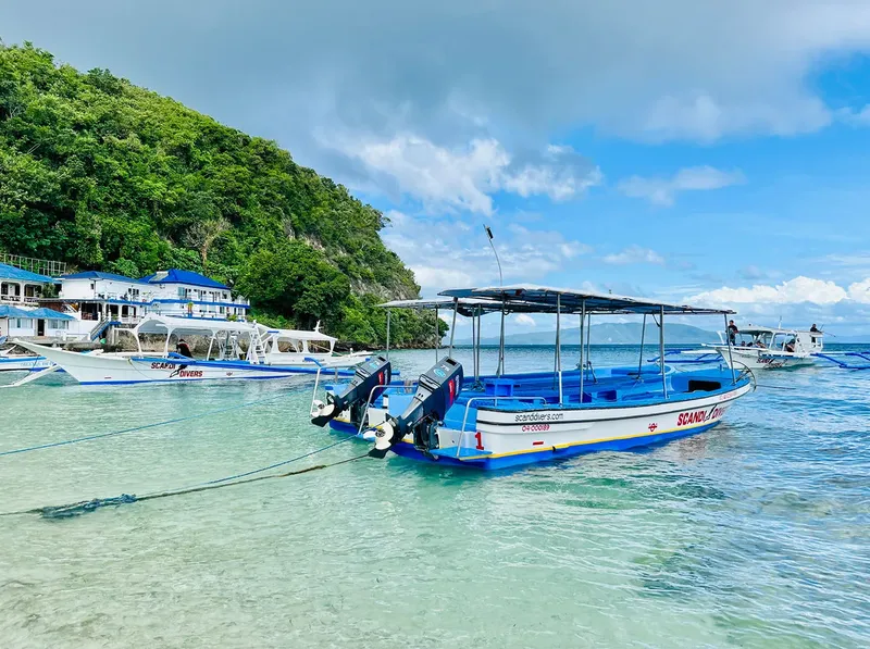 Plage tropicale avec bateaux de plongée amarrés devant un centre