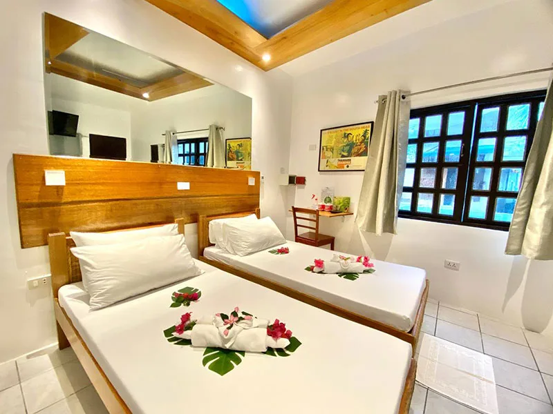Chambre d'hôtel avec deux lits simples, décoration florale et miroir