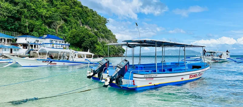 Plusieurs bateaux de plongée amarrés dans une baie turquoise ensoleillée