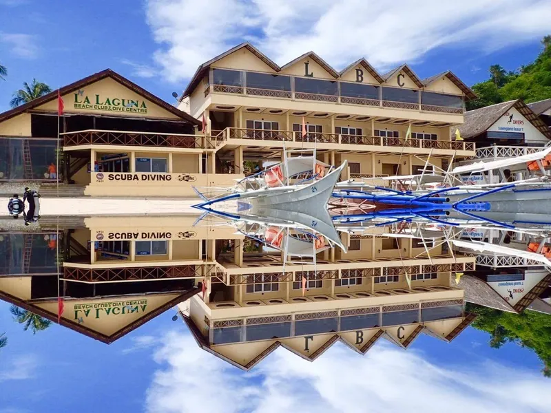 Bâtiment du centre de plongée et bateaux se reflétant dans l'eau