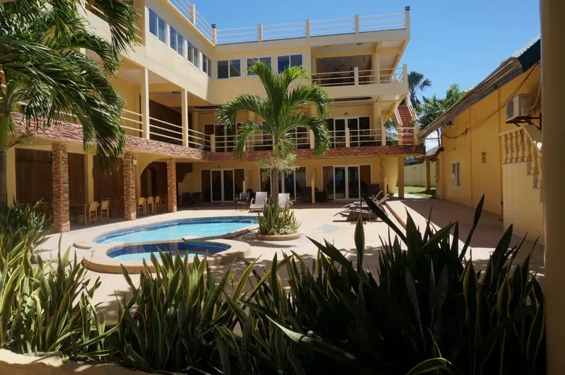 Bâtiment jaune avec piscine et végétation tropicale ensoleillée