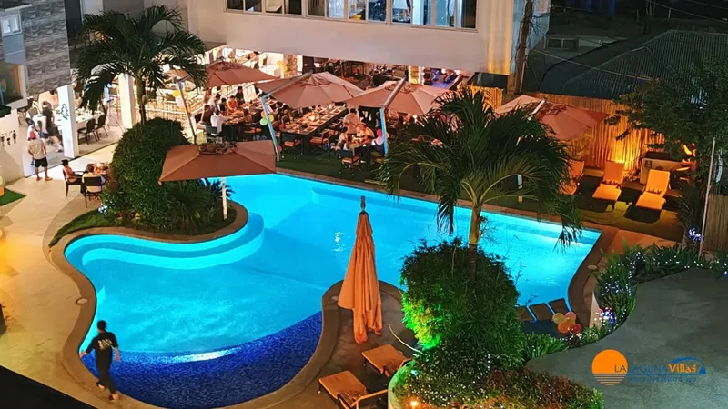 Vue nocturne d'une piscine illuminée avec des personnes et des parasols