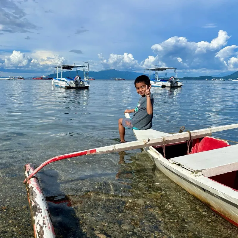 Un enfant souriant assis dans un bateau sur l'eau calme