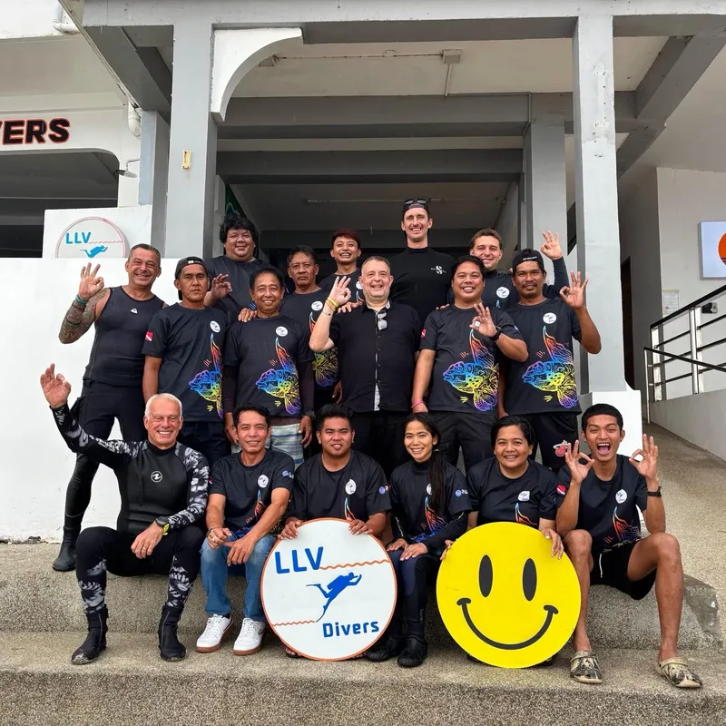 Groupe de personnes souriantes devant un bâtiment avec des logos LLV Divers