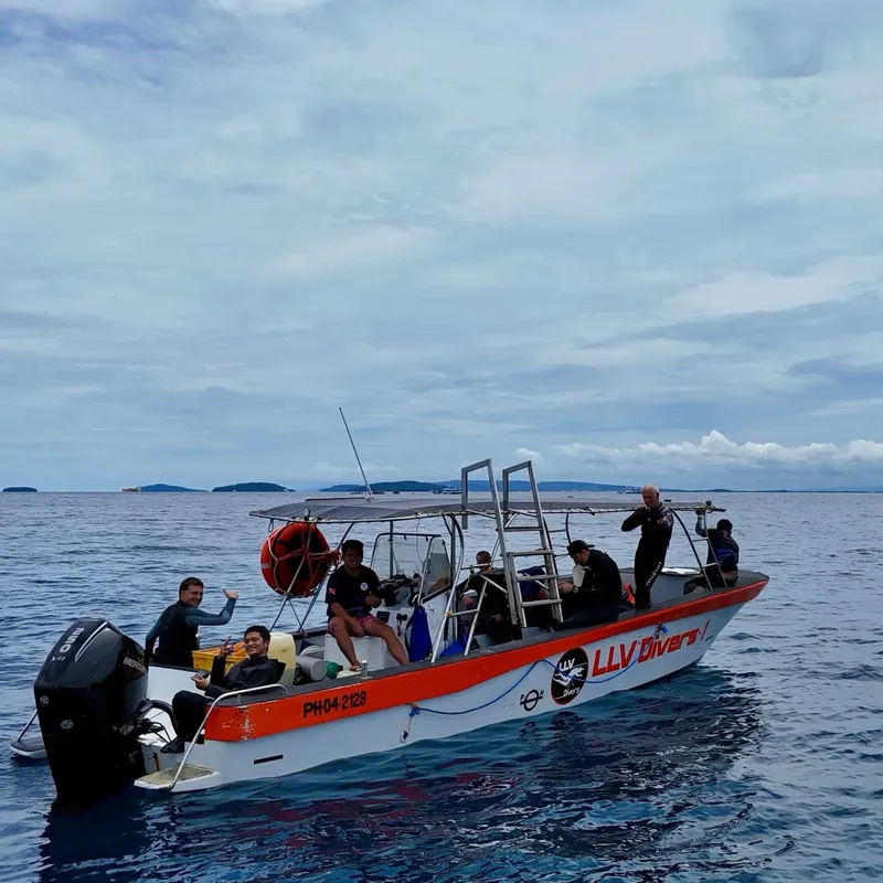 Bateau de plongée orange et blanc avec des plongeurs à bord en mer