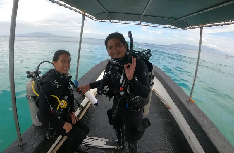Deux plongeuses souriantes sur un bateau en direction d'un site