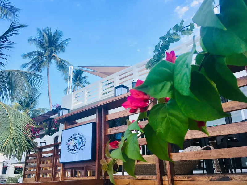 Façade d'un bâtiment avec un logo, des plantes et des palmiers