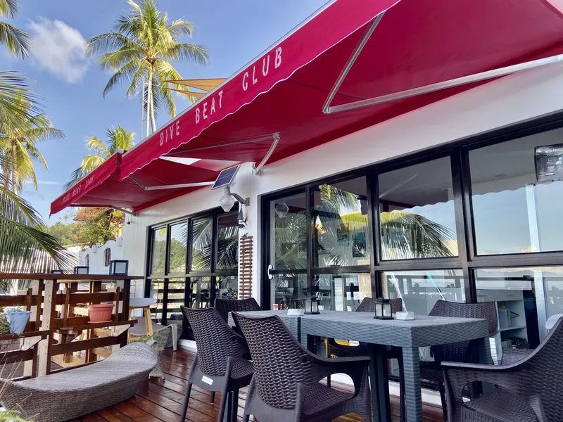Terrasse d'un club de plongée avec auvent rouge et mobilier extérieur