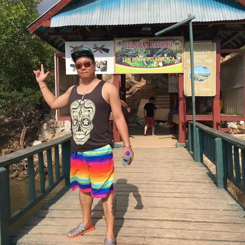 Homme souriant devant l'entrée d'un parc national tropical