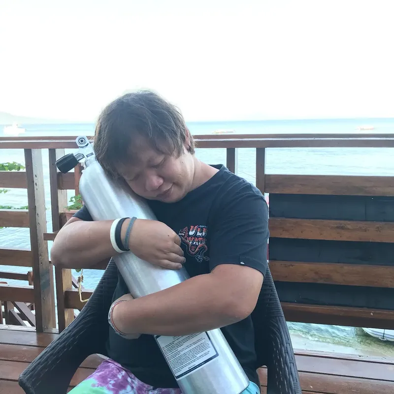 Un plongeur serre une bouteille d'air sur une terrasse ensoleillée