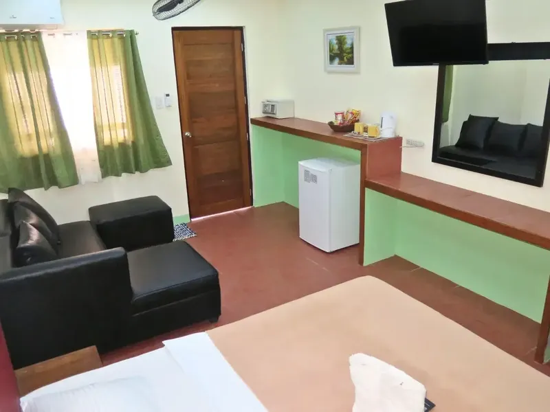 Chambre d'hôtel avec canapé, télévision, réfrigérateur et décoration tropicale