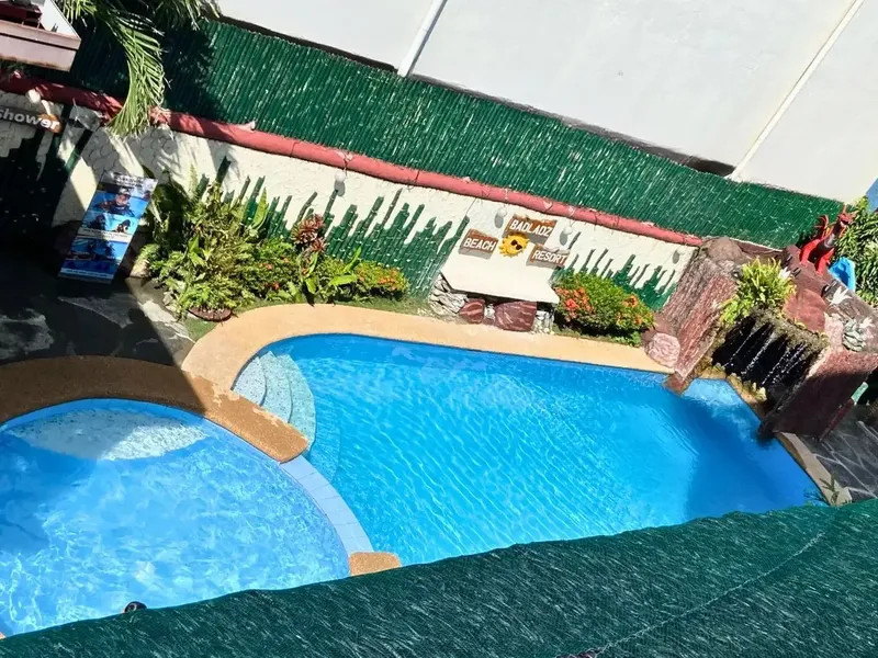 Piscine turquoise avec végétation luxuriante et enseigne de resort