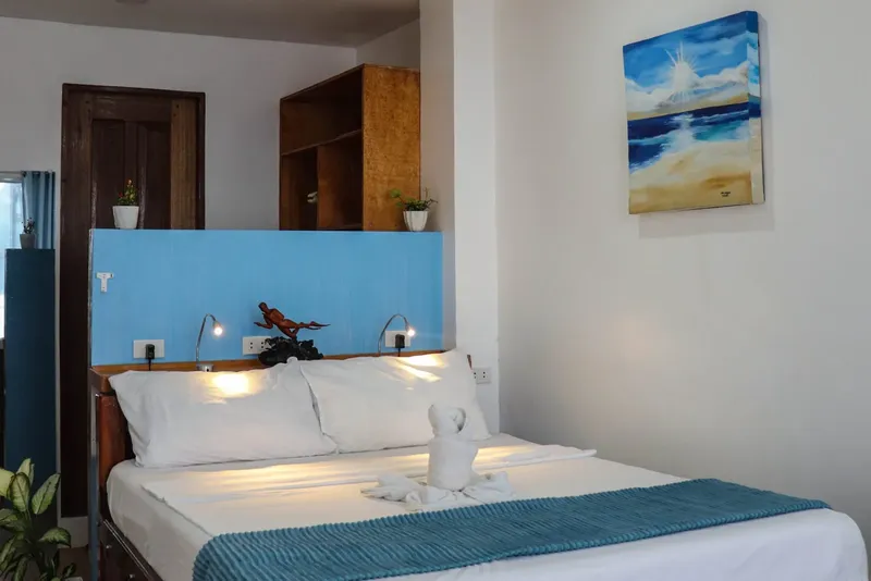 Chambre d'hôtel avec lit fait, décoration marine et tableau de plage