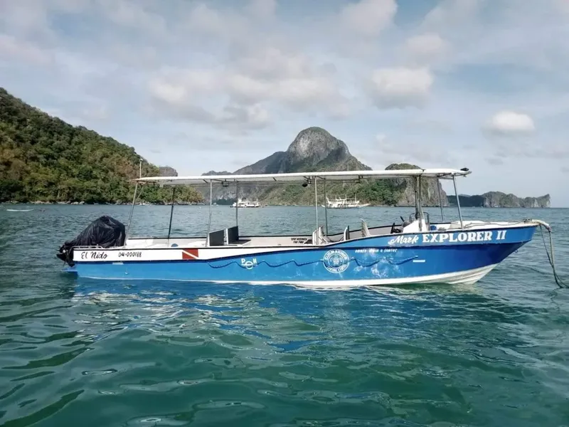 Bateau de plongée bleu et blanc naviguant sur une mer turquoise