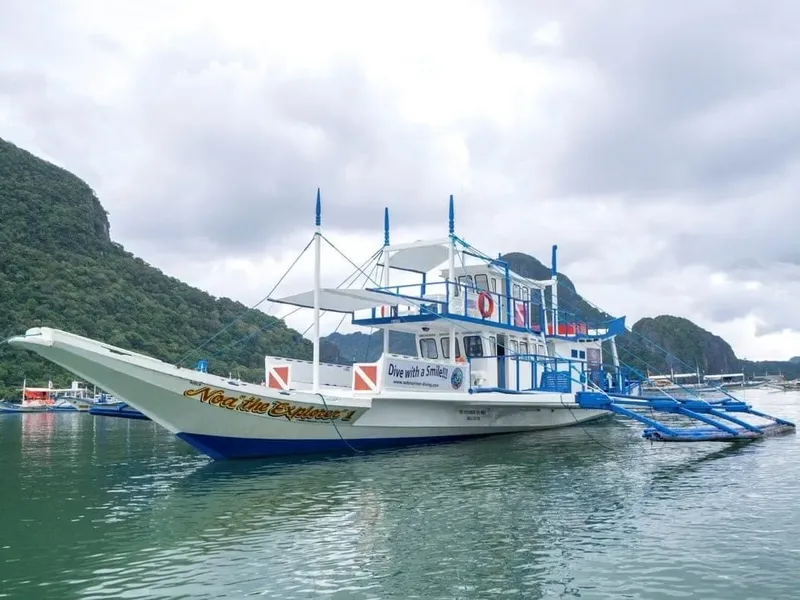 Bateau de plongée blanc et bleu amarré dans une baie tropicale