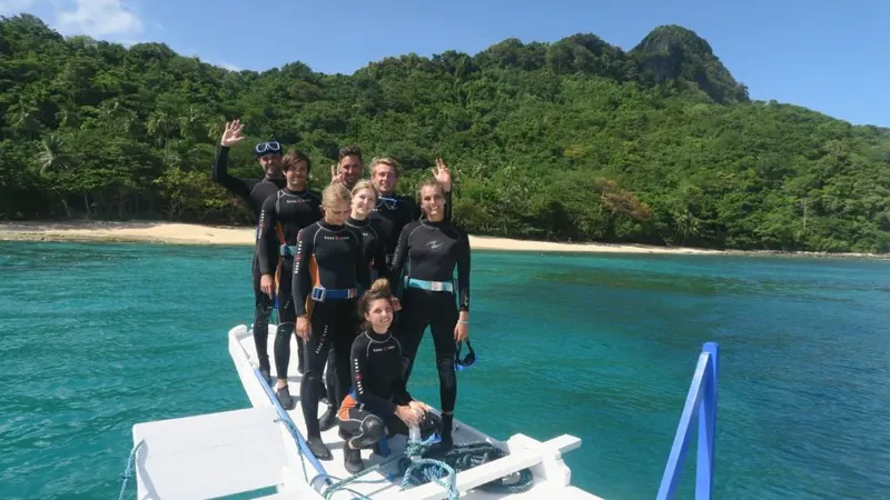 Groupe de plongeurs souriants sur un bateau en mer turquoise