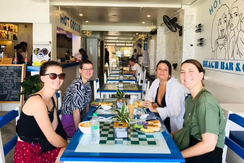 Cinq personnes souriantes assises à une table dans un café lumineux