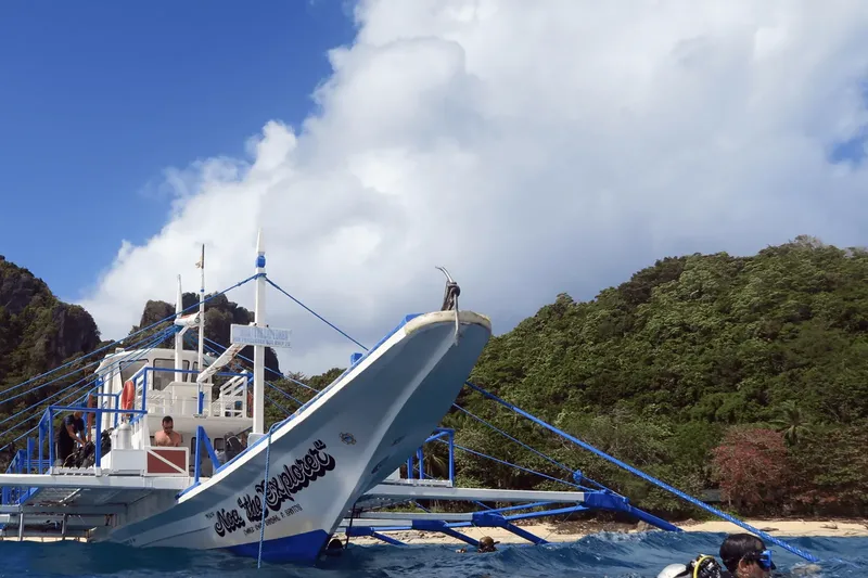 Bateau de plongée amarré près d'une plage avec des passagers à bord