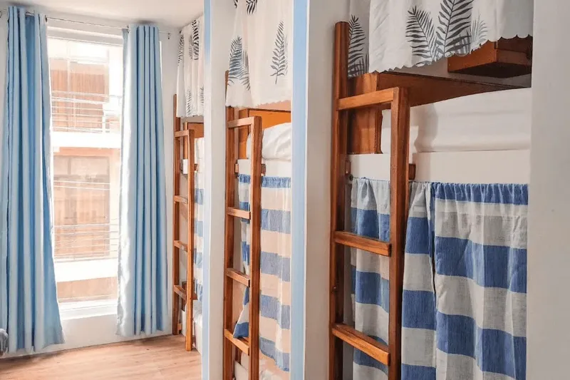 Lits superposés dans une chambre claire avec rideaux bleus et blancs