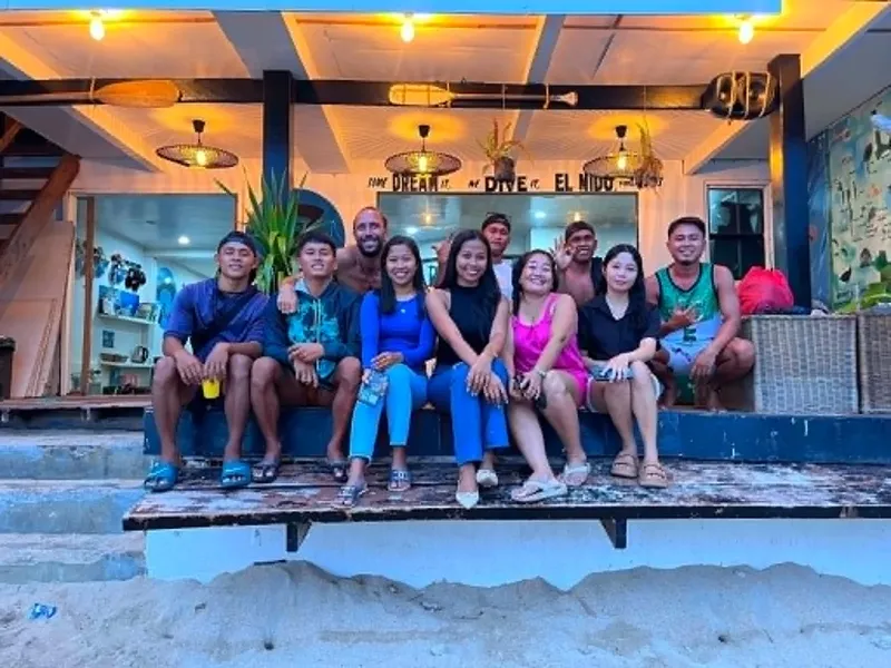 Groupe de personnes souriantes posant devant un centre de plongée tropical